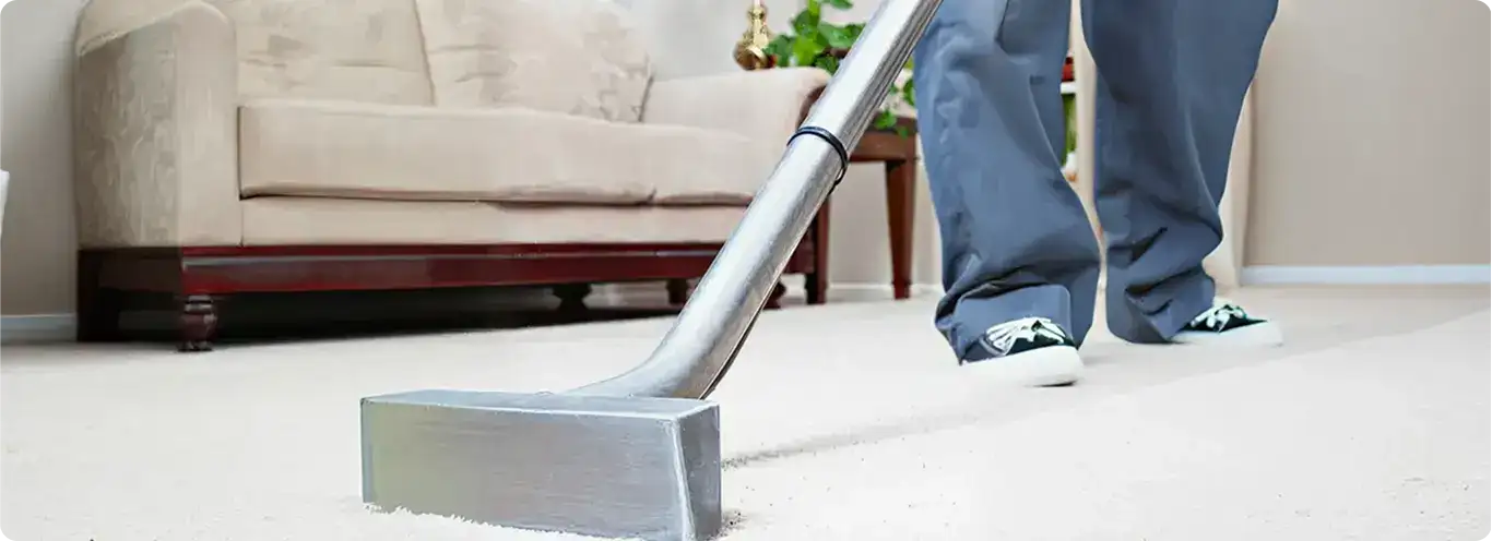 Carpet cleaning technician using a hot-water extraction wand on a light-colored carpet in a living room, Louisville, KY.